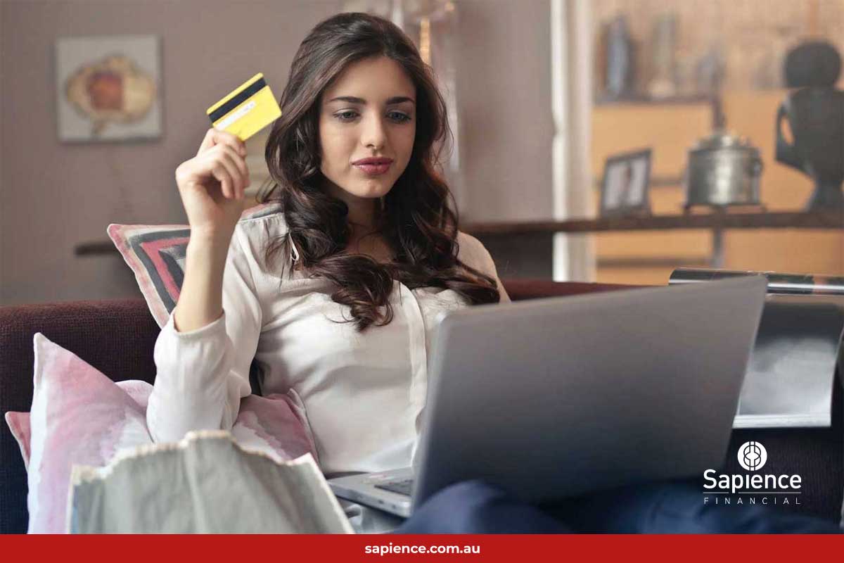 person sitting in front of laptop computer thinking about using a credit card for a purchase