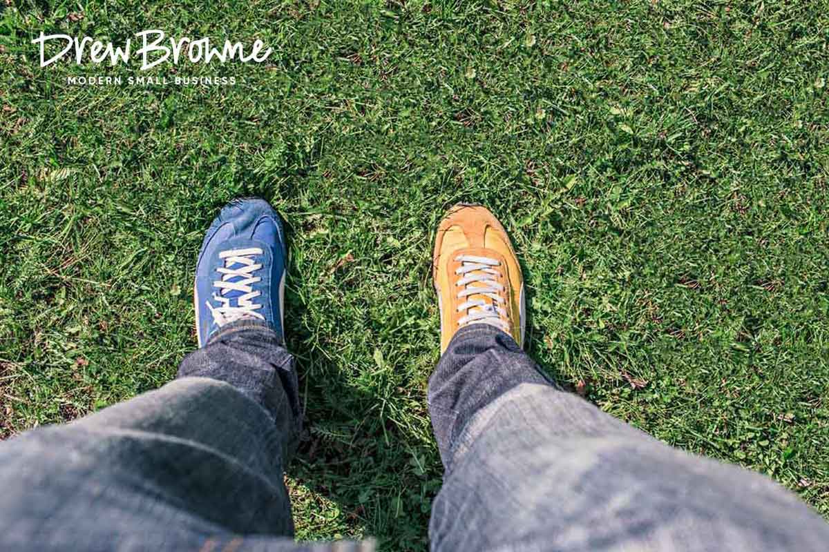 A top down view of a person in jeans wearing a blue shoe and a yellow shoe