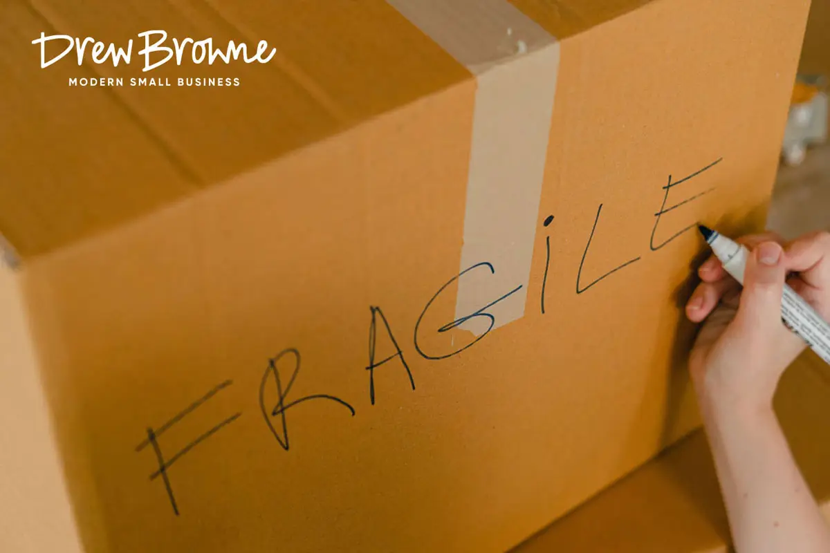 writing the word fragile on a cardboard moving box