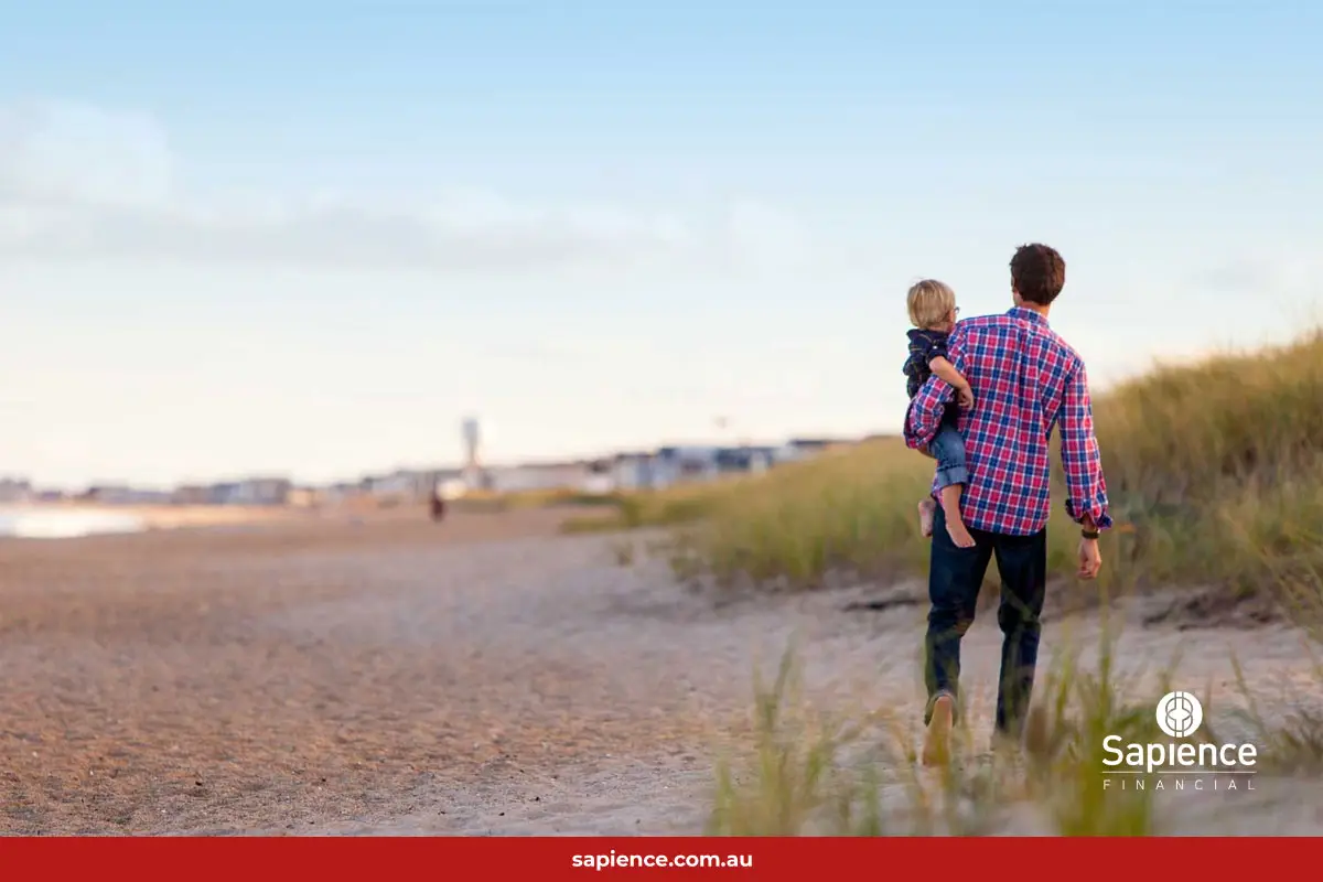 father walking on beach with child on his hip