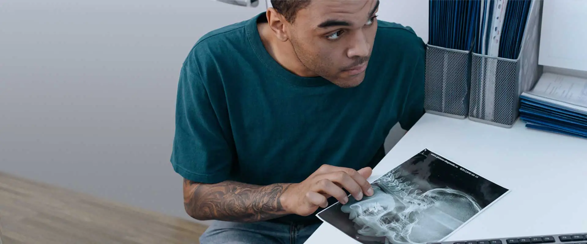 young man with arm tattoos in doctors office discussing a head xray scan