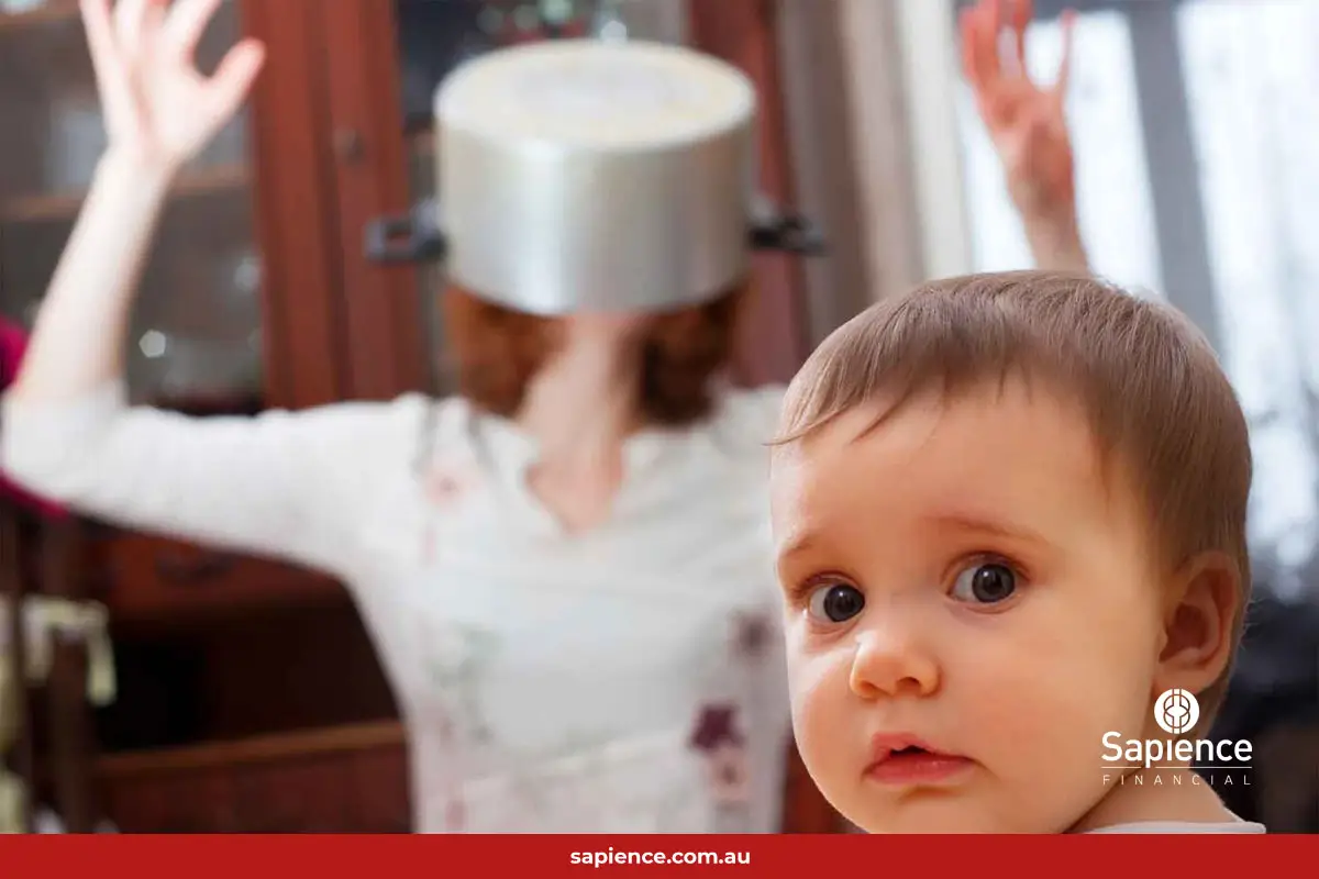 mother with a saucepan over her head watched by a confused baby